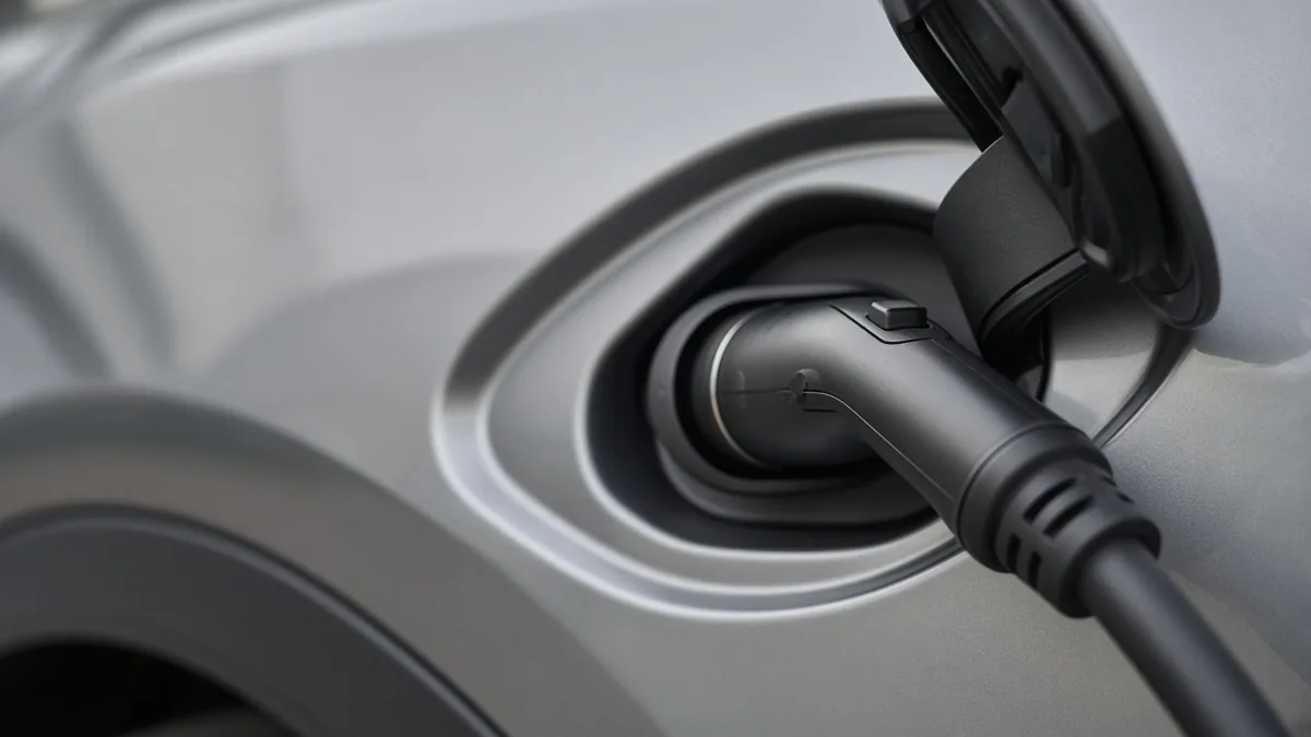 Close-up of a charging connector plugged into the charging port of a silver car